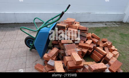 Ein Haufen Ziegelsteine mit blauen Schubkarre oder Bau-Wagen Stockfoto