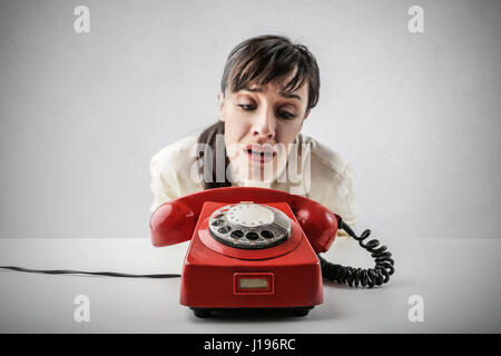 Brünette Frau leider betrachten rote retro Telefon Stockfoto