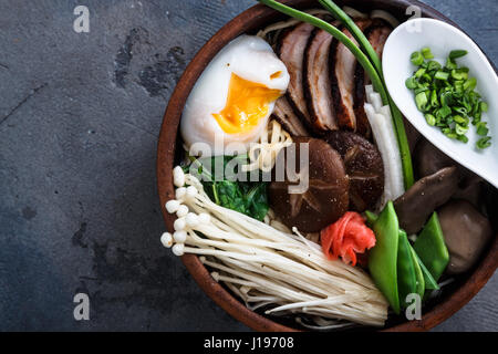 Schüssel Ramen-Nudeln mit Ei, Enoki, Shiitake-Pilze, Ente und Zwiebeln Stockfoto