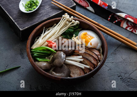 Schüssel Ramen-Nudeln mit Ei, Enoki, Shiitake-Pilze, Ente und Zwiebeln Stockfoto