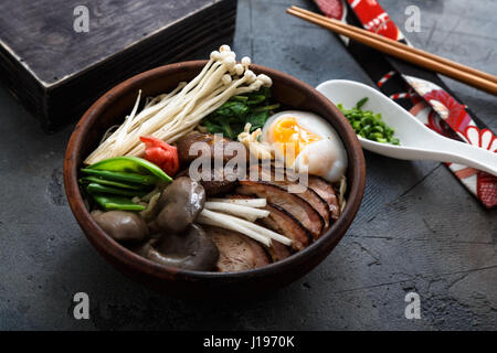 Schüssel Ramen-Nudeln mit Ei, Enoki, Shiitake-Pilze, Ente und Zwiebeln Stockfoto