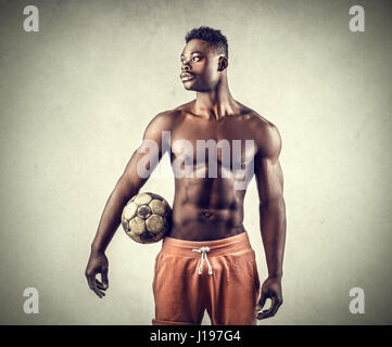 Muskulöser Mann halten Fußball Stockfoto