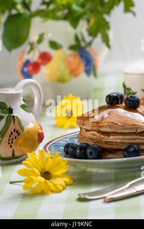 Frühstück Landschaft: leckere Pfannkuchen mit Heidelbeeren mit buntem Obst Thema Tee-Set. Stockfoto