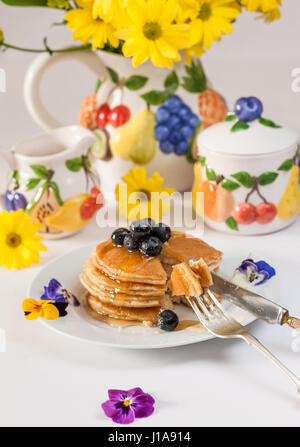 Frühstück Landschaft: leckere Pfannkuchen mit Heidelbeeren mit buntem Obst Thema Tee-Set. Stockfoto