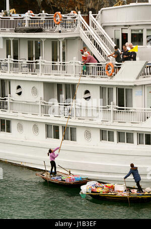 Fischers Familien in der Halong Bay zum Familieneinkommen beitragen, indem Sie mit Snacks und Souvenirs, die vorbeifahrenden Ausflugsboote. Stockfoto