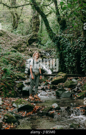 Kaukasische Frau Rucksackreisen in Waldbach Stockfoto