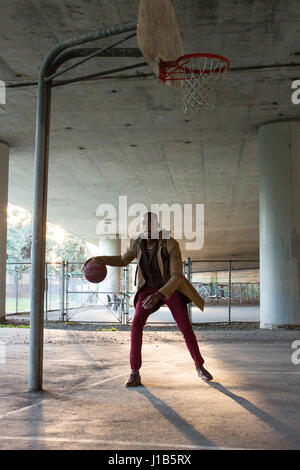 Schwarzer Mann mit Rucksack Basketballspielen unter Überführung Stockfoto