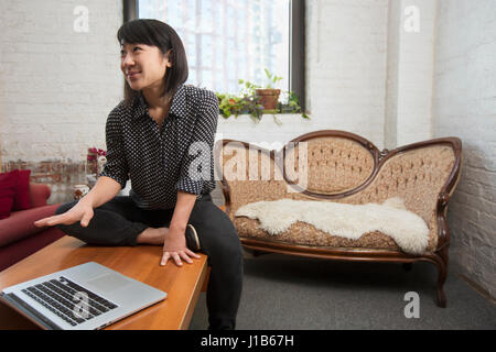Asiatische Frau, die in der Nähe von Laptop gestikulieren Stockfoto
