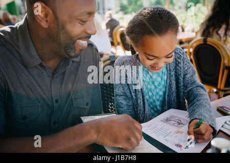 Vater beobachtete Tochter Färbung mit Kreide im restaurant Stockfoto
