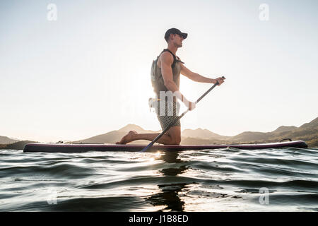 Kaukasischen Mann kniet auf Paddleboard im Fluss Stockfoto