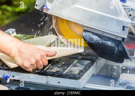 Mit Hilfe ein Diamanten bestückte Sägeblatt Kreissäge schneiden durch eine keramische Bodenfliese Stockfoto