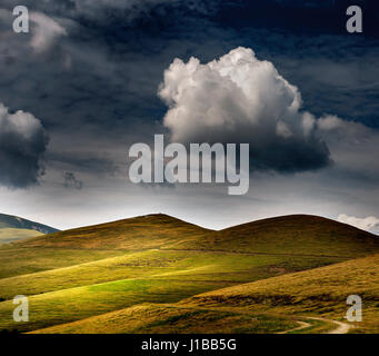 Wählen Sie alle bestanden Landschaft mit grünen Hügeln und dunkle Wolken Stockfoto