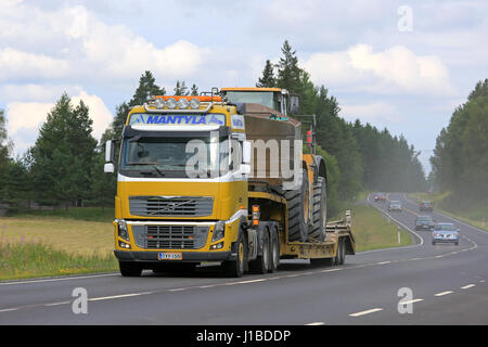 SALO, Finnland - 30. Juli 2016: Gelb Volvo FH16 halb Mantyla E & E Transporte Caterpillar 980 H Radlader auf Drop Deck Trailer auf ländlichen Autobahn bei Stockfoto