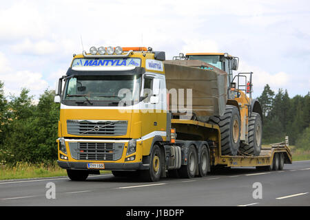 SALO, Finnland - 30. Juli 2016: Gelb Volvo FH halb Mantyla Transporte Caterpillar 980 H Radlader auf Drop Deck Trailer auf ländlichen Autobahn bei Summe Stockfoto