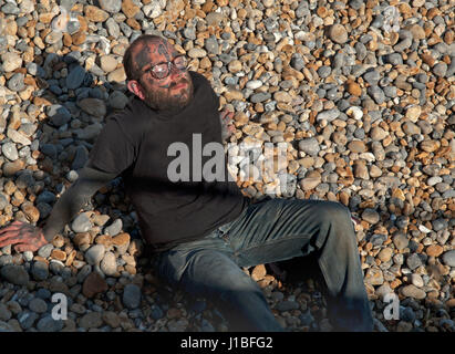 Ein stark tätowierter Mann sonnt sich am Strand in Brighton Stockfoto