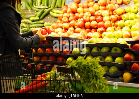 Eine Frau für Äpfel an einem Lebensmittelgeschäft oder Supermarkt einkaufen Stockfoto