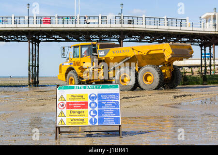 Website-Sicherheitszeichen auf Baustelle am Strand. Volvo A25E artikuliert Schlepper bewegen Schindel auf Worthing Strand, Worthing, West Sussex, England, UK. Stockfoto