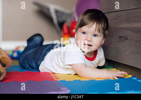 1 Jahr alt. Glückliches Baby junge liegt auf Boden im Kinderzimmer sowie spielen. Stockfoto