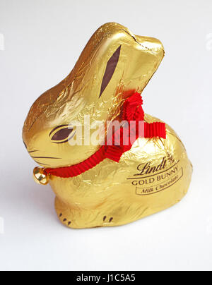 Ein Lindt Milchschokolade Goldhase mit roter Schleife für ein Geschenk zu Ostern. Stockfoto