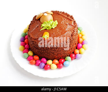 Ein dekorierter hausgemachter Schokoladenkuchen, umgeben von kleinen Ostereiern. Stockfoto