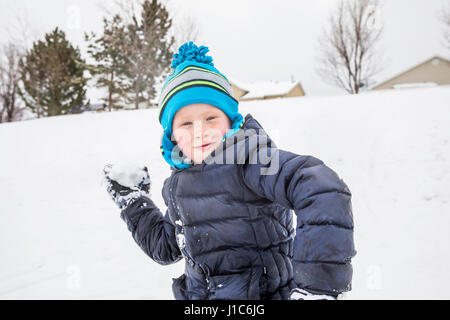 Lächelnde junge werfen Schneeball im winter Stockfoto