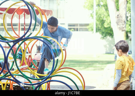 Hispanische Jungs Klettern auf Struktur auf Spielplatz Stockfoto