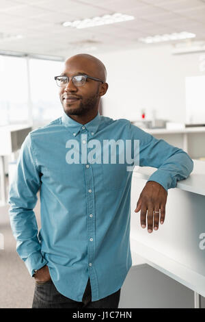 Lächelnder afroamerikanische Mann lehnt sich im Büro Stockfoto