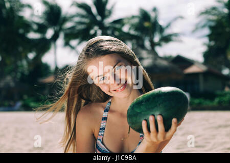 Kaukasische Frau hält Wassermelone am Strand Stockfoto