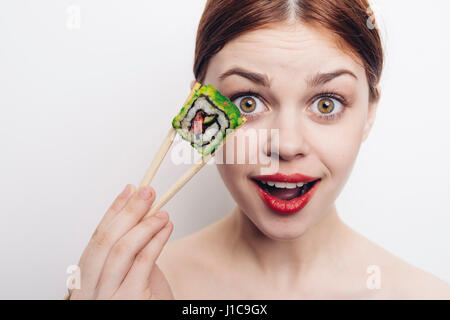 Kaukasische Frau hält Sushi mit Stäbchen Stockfoto