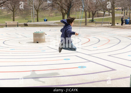 ZEHN JAHRE ALTEN SPRINGT SEIL AN WARMEN FRÜHLINGSTAG IM CHRISTIE GRUBEN PARK IN TORONTO, KANADA. Stockfoto