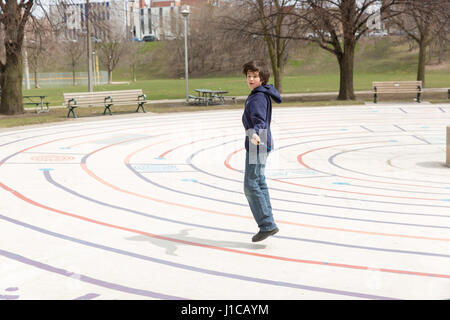 ZEHN JAHRE ALTEN SPRINGT SEIL AN WARMEN FRÜHLINGSTAG IM CHRISTIE GRUBEN PARK IN TORONTO, KANADA. Stockfoto