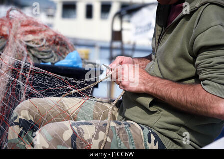 Hände bei der Arbeit am Fischernetz mit einem Werkzeug Stockfoto