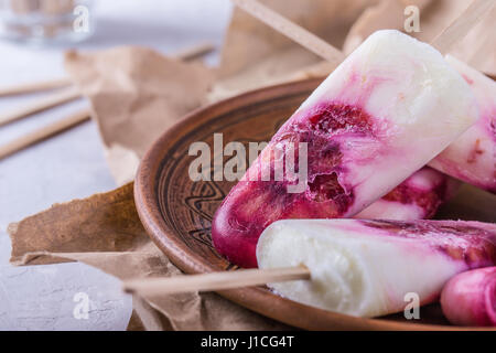 Hausgemachtes Joghurt Eis am Stiel dekoriert mit Blutorange Scheiben Onceramic Platte über rustikale graue Leuchttisch Stockfoto