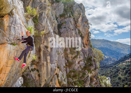 Seitenansicht einer Frau auf eine Leiter klettern den Berg hinauf. Horizontal im Freien gedreht Stockfoto