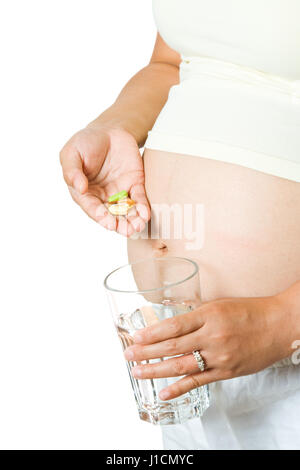 Eine isolierte Aufnahme einer schwangeren Frau, die Einnahme ihrer Medikamente/Vitamin mit einem Glas Wasser Stockfoto
