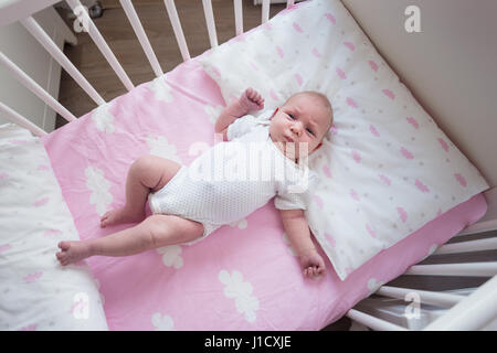 Zwei Wochen alten Baby Mädchen schläft in ihrem Bettchen auf pink Sheets mit Wolkenmuster. Stockfoto