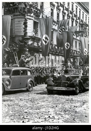 Führer Adolf Hitler kehrt am 4. Juli 1940 in einem offiziellen Mercedes im offenen Spitzenfeld in der klassischen "Sieg Heil"-Pose nach Berlin zurück, um nach seinem Besuch im vom Nazi besetzten Paris und seinem militärischen Erfolg in ganz Frankreich deutsche Menschenmassen, Nazi-Sturmtrupps, Blumenstreustraßen, Filmkameras und Swastika-Flaggen zu schmückern Stockfoto