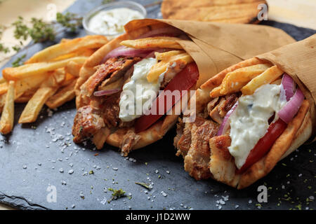 Griechische Gyros in Pita Brot auf einem schwarzen Teller gewickelt Stockfoto