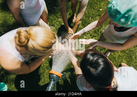 junge Frauen waschen ihre Hände im Garten an einem heißen Sommertag Stockfoto