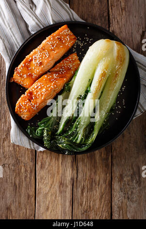 Verglaste Lachsfilet mit Sesam und gebratenen Kohl Bok Choy Nahaufnahme auf einer Platte. Vertikale Ansicht von oben Stockfoto