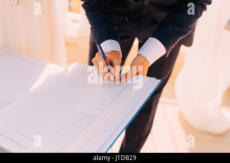 Brautpaar setzen ihre Unterschriften im Akt der Registrierung einer Ehe Stockfoto