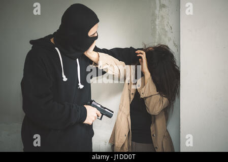 Geisel der Terrorist oder Einbrecher droht mit Waffe in verlassenen Gebäude Stockfoto