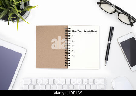 Neujahr Resolutionen Konzept mit offen, Notizbuch, Stift, Handy, Tablet, kleine Pflanze und Brillen auf weißen Schreibtisch Stockfoto