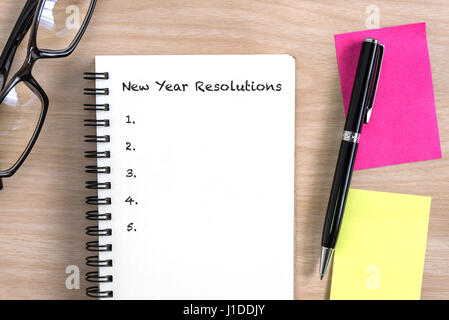 Neujahr Resolutionen Konzept mit offen, Notizbuch, Stift, bunte Haftnotizen und Brillen auf Schreibtisch aus Holz Stockfoto