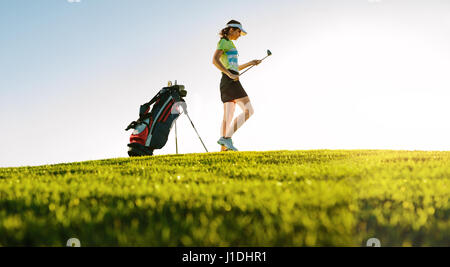 Niedrigen Winkel Schuss professionelle weibliche Golfer am Golfplatz. Gesamte Länge der Golfspieler mit Golf-Stick auf Feld. Stockfoto