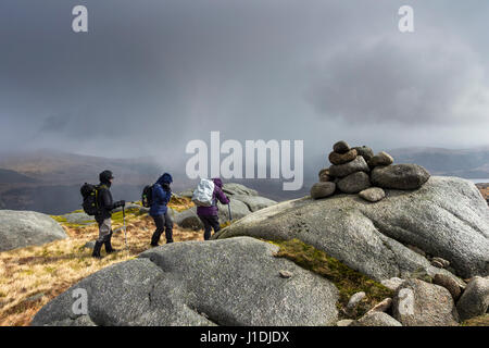 Wanderer auf dem Gipfel des Criagnaw verspannen sich gegen den Wind, wie eine schwere Schnee Bö sie, Galloway Hills, Schottland trifft Stockfoto