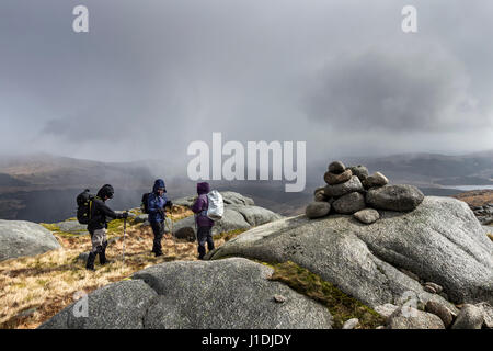 Wanderer auf dem Gipfel des Criagnaw sich gegen eine schwere Bö Verstrebungen, während Schlechtwetter, Galloway Hills, Schottland durchläuft Stockfoto