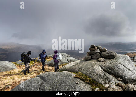 Wanderer auf dem Gipfel des Criagnaw verspannen sich gegen den Wind, wie eine schwere Schnee Bö sie, Galloway Hills, Schottland trifft Stockfoto