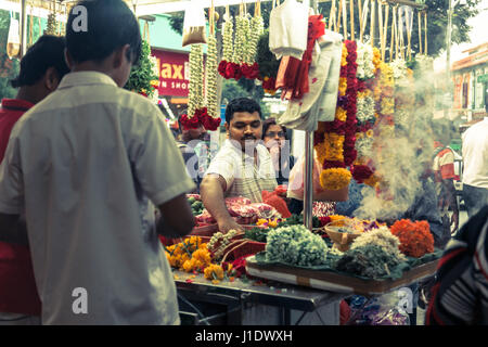 Eine indische Straße Verkäufer Verkauf von Blumen und Girlanden in einer geschäftigen Straße Markt in wenig Indien, Singapur, Südostasien Stockfoto