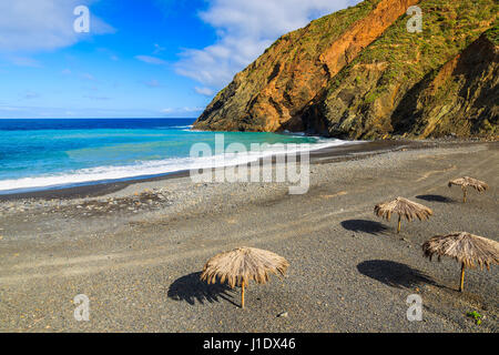 Sonnenschirme am Kiesel Strand Playa de Vallehermoso auf der Insel La Gomera, Spanien Stockfoto